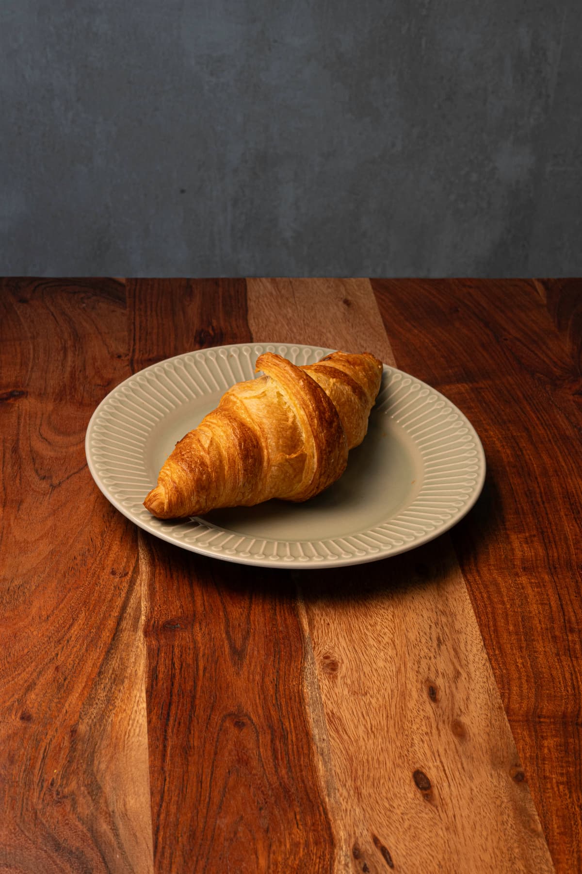 Croissant recién horneado servido sobre una mesa de madera