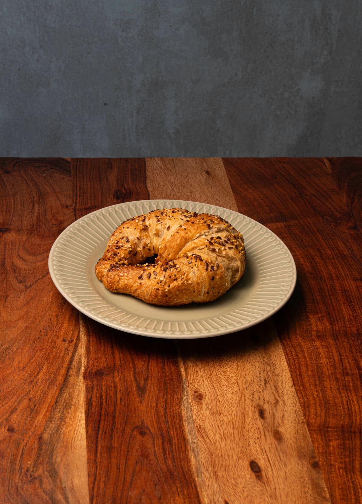 Croissant de semillas servido en un plato sobre una mesa de madera