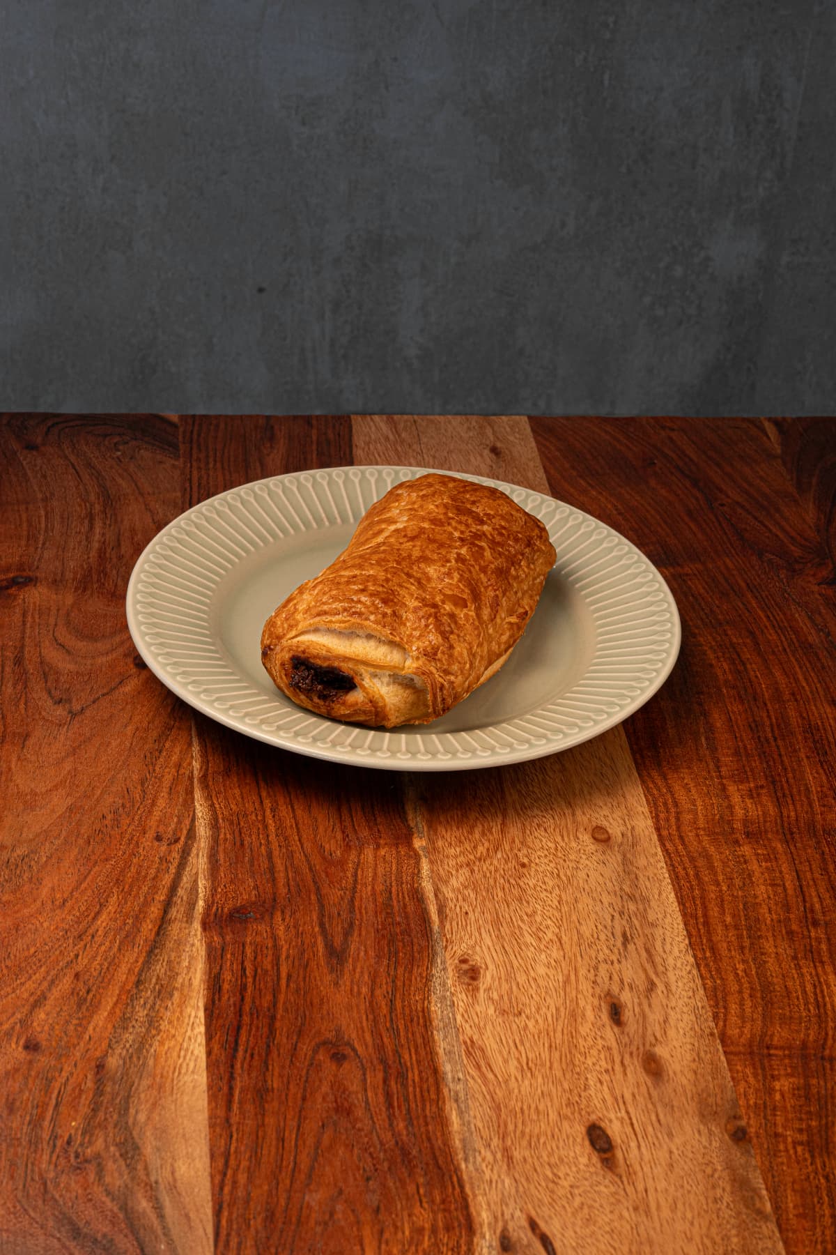 Napolitana de chocolate servida en un plato sobre una mesa de madera