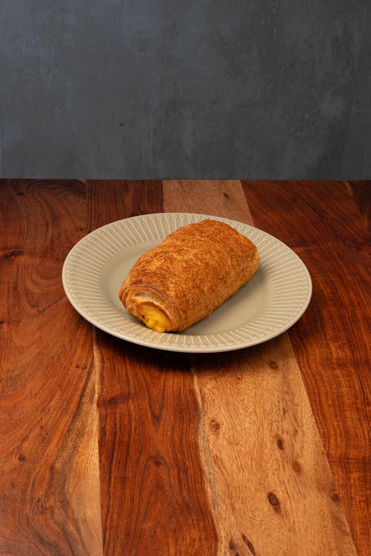 Napolitana de crema servida en un plato sobre una mesa de madera